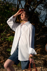 Person wearing a white shirt and denim shorts outdoors with a basket.