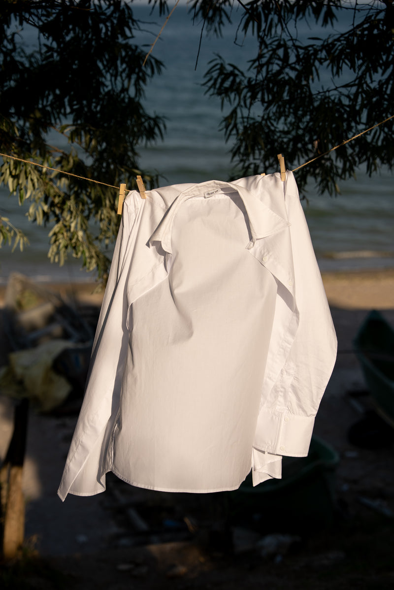 White shirt hanging on a clothesline by a body of water